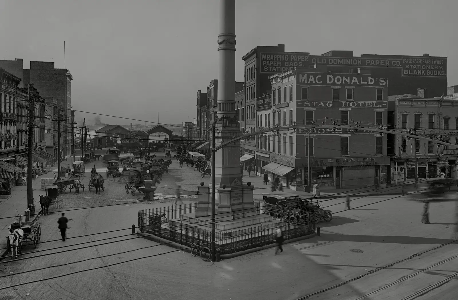 Horse carts, wagons, early automobiles and trolley wires crowd Commercial Place in downtown Norfolk.